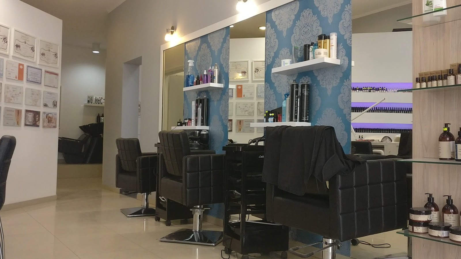 Wnętrze salonu ze stanowiskami fryzjerskimi i niebieską ozdobną tapetą